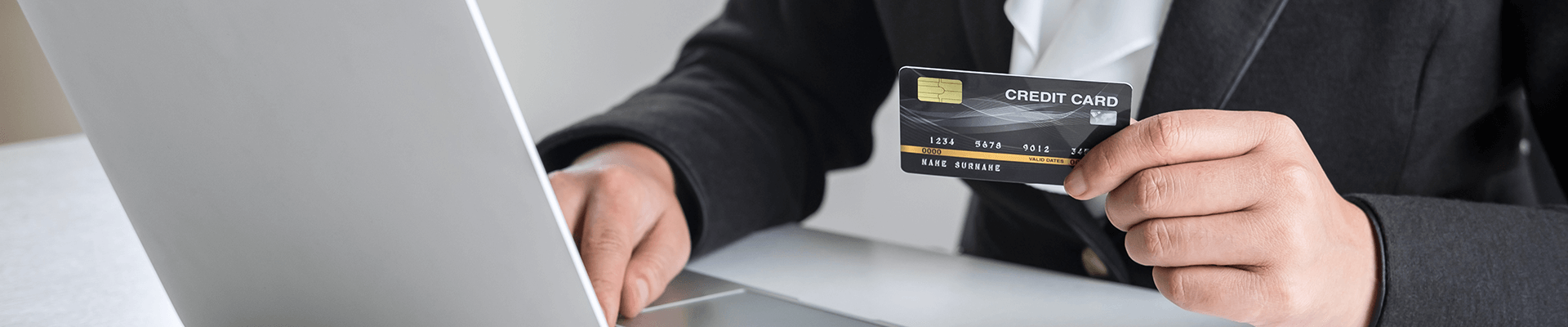 Una mano sosteniendo una tarjeta de pago en frente de un computador